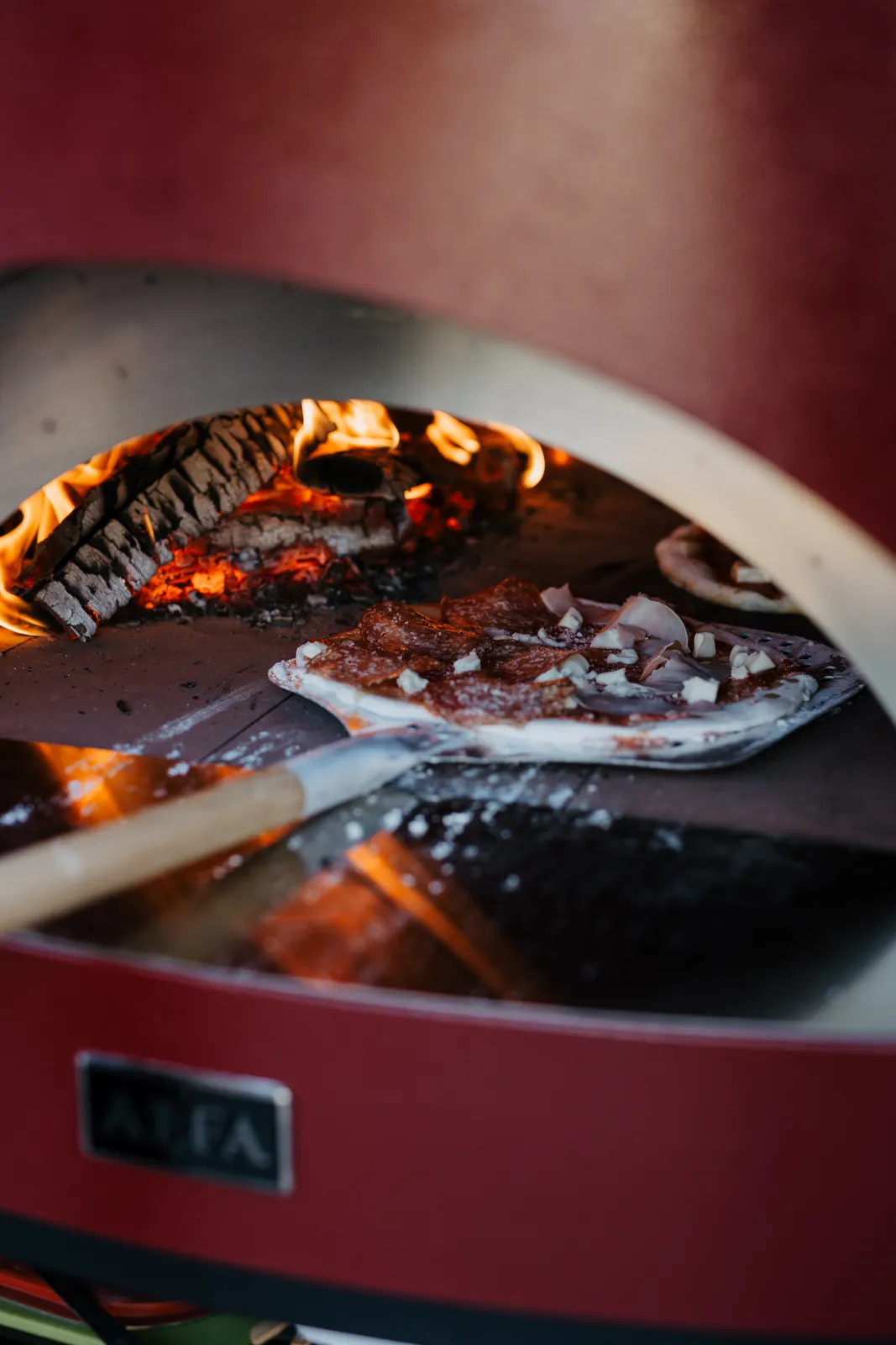 Frische Pizza im Holzofen mit Feuer